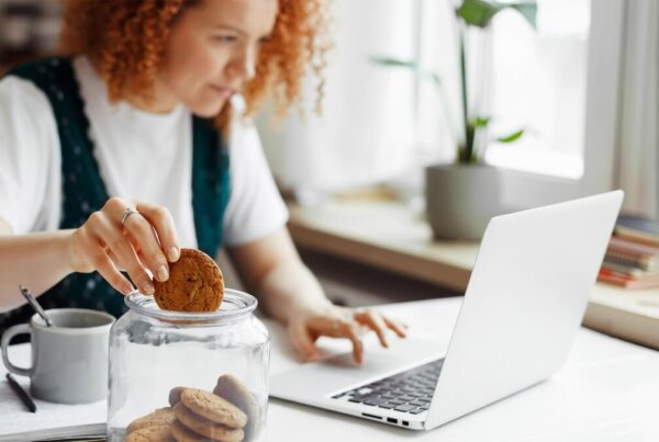 Woman working on laptop while holding a cookie